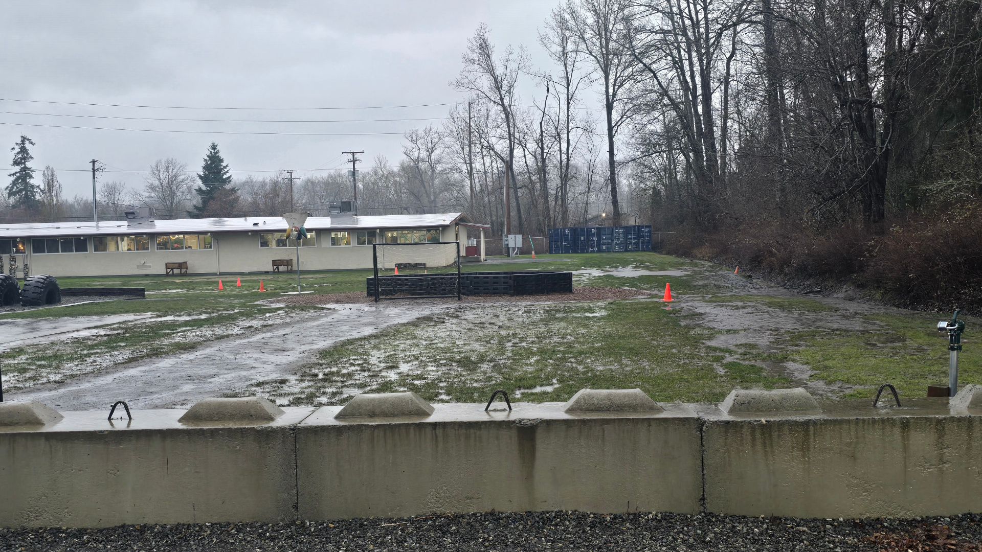 The Sunset Campus field on a rainy day — patches of mud, standing water, and worn grass